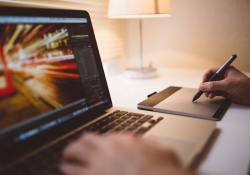 person writing while using a laptop