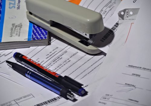 Stapler, papers, and pens on a desk